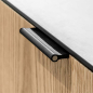 Preview: Close-up of a black VERONA recessed leather pull with brass rod fitted into a furniture front