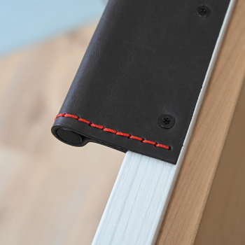 Schwarzer Pull Edge Handle KENT mit roter Ziernaht an einer offenen Schubladentür