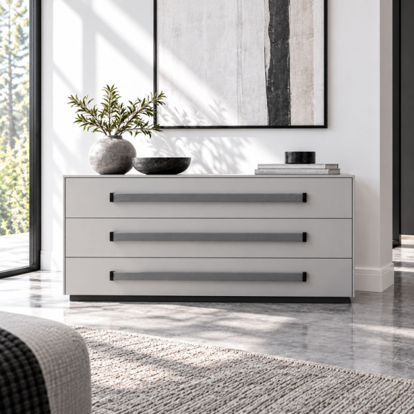 Three long grey ROMA leather handles with black mounting bases on a minimalist chest of drawers